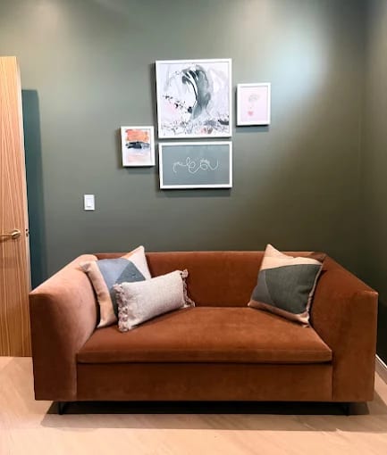 A velvet sofa and framed artwork in a calm corner of Dr. Levi's office